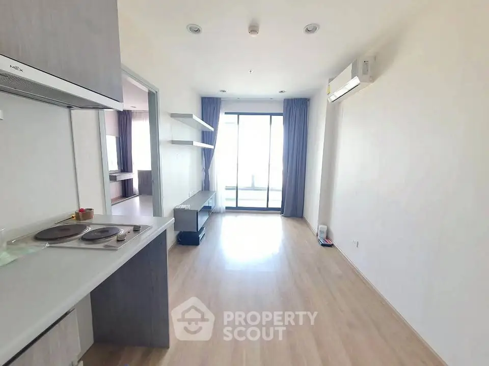 Bright modern living room with open layout and balcony access, featuring sleek flooring and air conditioning.