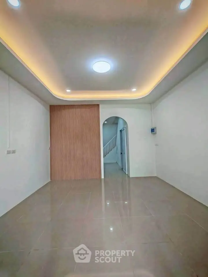 Spacious modern living room with elegant ceiling lighting and glossy tiled floors.