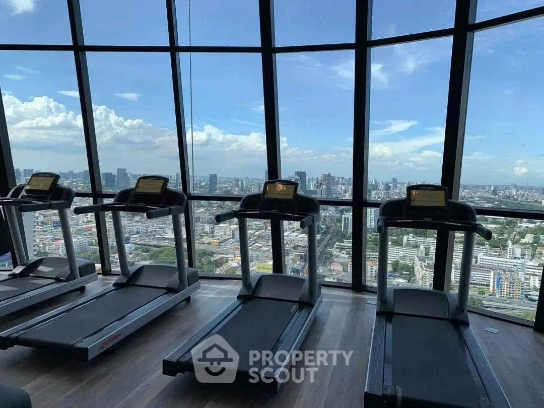 Stunning gym with panoramic city views from high-rise building, featuring modern treadmills and floor-to-ceiling windows.