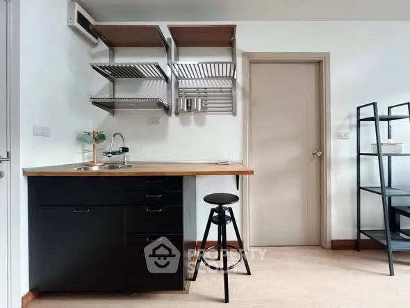 Modern kitchen with sleek black cabinets and open shelving, featuring a minimalist design and compact layout.