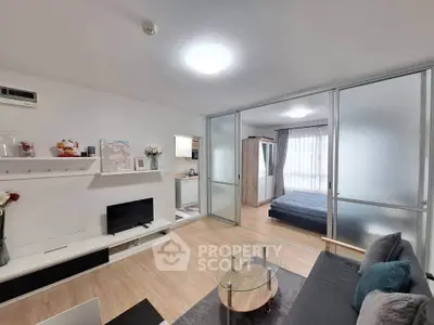 Modern open-plan living room with glass partition leading to cozy bedroom.