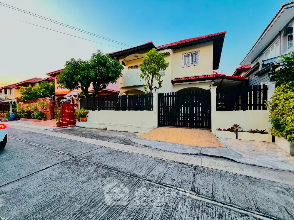 Charming suburban house with red roof and fenced yard in a peaceful neighborhood.