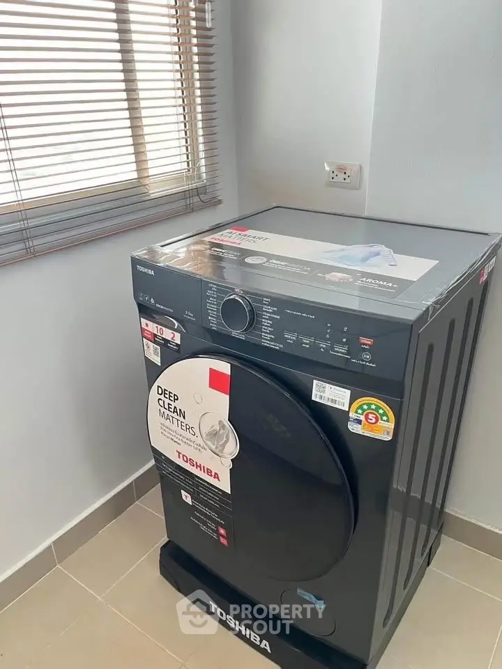 Brand new Toshiba washing machine in a modern laundry room with natural light.