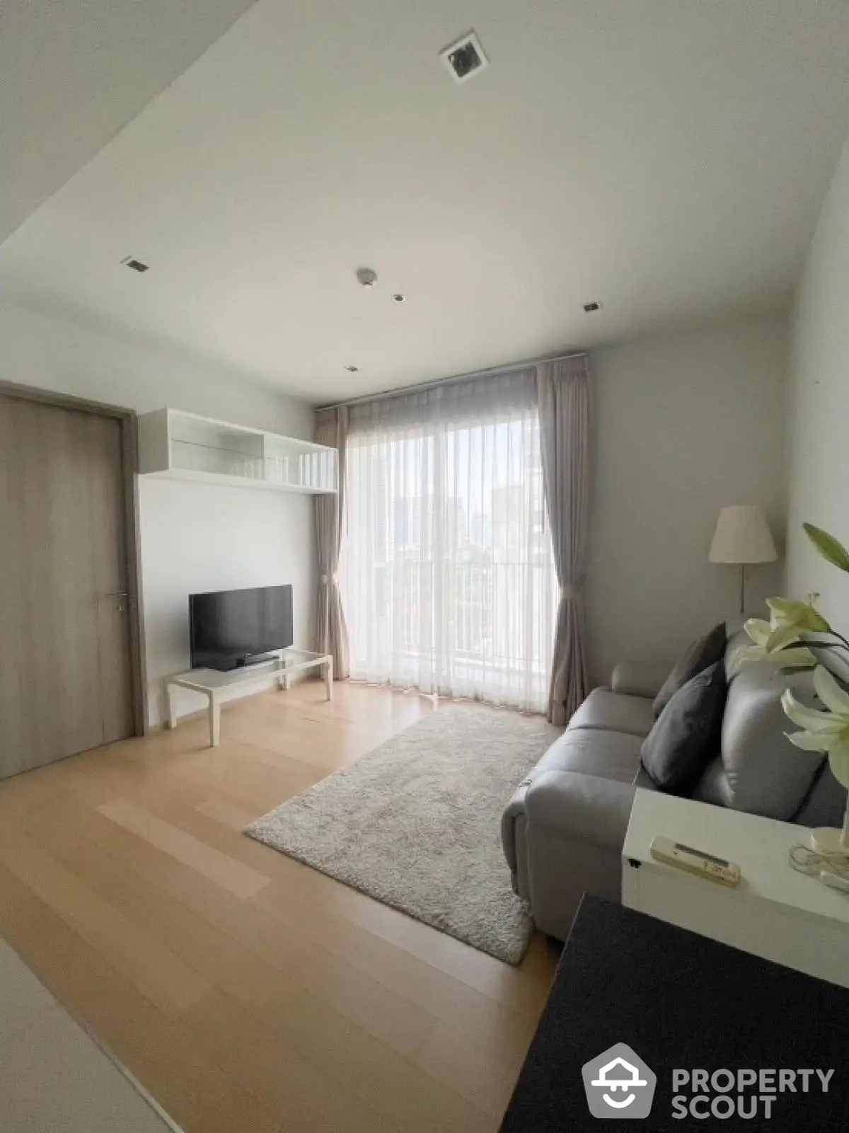 Modern living room with sleek design, large window, and cozy seating area in a bright apartment.