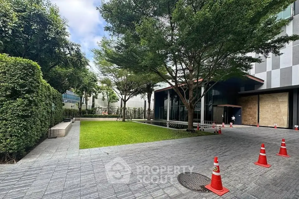 Modern building entrance with lush green garden and paved walkway