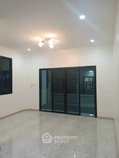Spacious living room with marble flooring and sliding glass doors leading to balcony.
