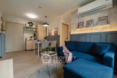 Modern living room with stylish blue sofa and dining area, featuring elegant decor and air conditioning.