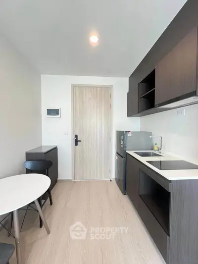 Modern kitchen with sleek cabinetry and compact dining area in a stylish apartment.