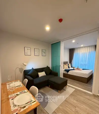 Modern open-plan living room with dining area and cozy bedroom view.