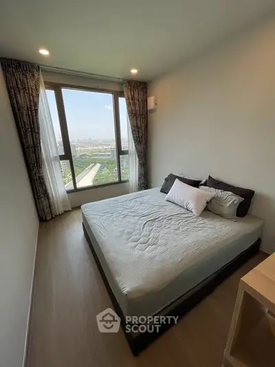Cozy bedroom with large window offering stunning city view, perfect for relaxation and comfort.
