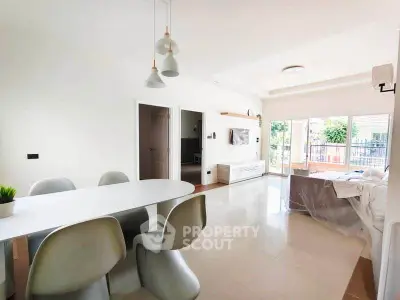 Spacious modern living room with dining area and large windows opening to a balcony.
