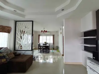 Spacious living room with modern decor and dining area, featuring elegant ceiling design and natural light.