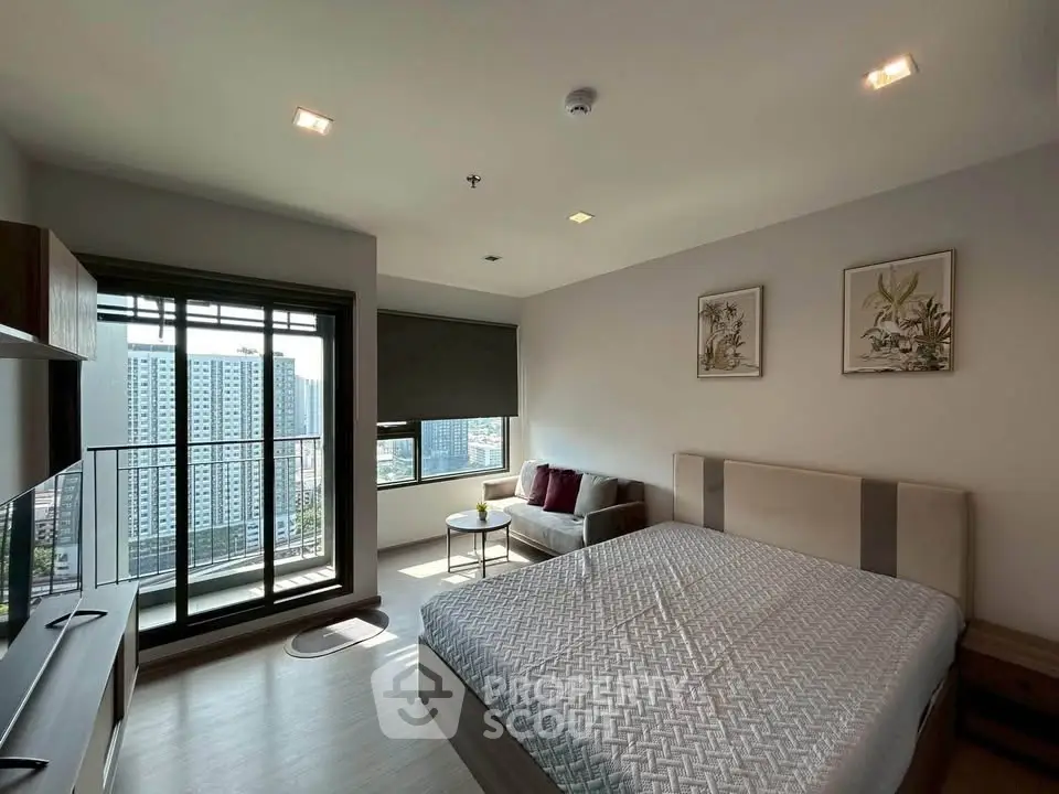 Modern bedroom with large window and city view, featuring stylish decor and cozy seating area.