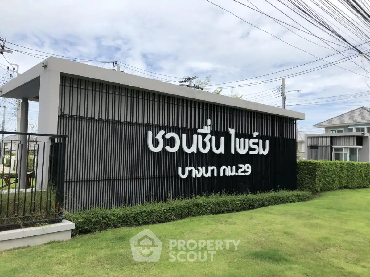 Modern residential entrance with stylish signage and lush greenery