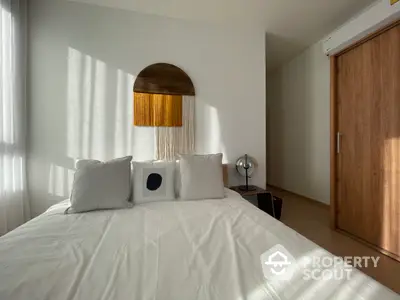 Sunlit minimalist bedroom with crisp white bedding, a unique half-moon headboard, and warm wooden accents creating a serene and inviting atmosphere.