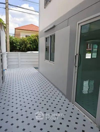 Modern exterior patio with tiled flooring and sliding glass door, perfect for outdoor relaxation.