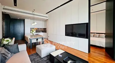 Modern open-plan living room with sleek kitchen and dining area, featuring elegant decor and wooden flooring.