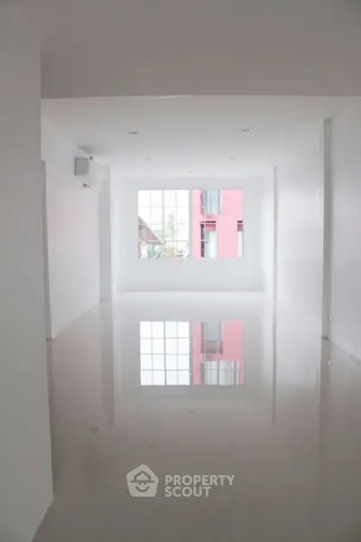 Spacious empty room with large window and glossy floor, perfect for customization.