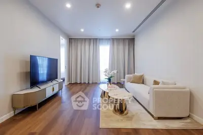 Modern living room with elegant decor and large TV, featuring wooden flooring and soft lighting.