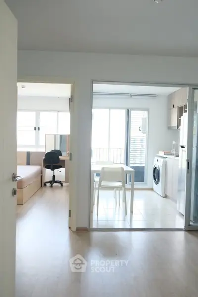 Modern apartment interior with open kitchen and washing machine, bright and airy design.