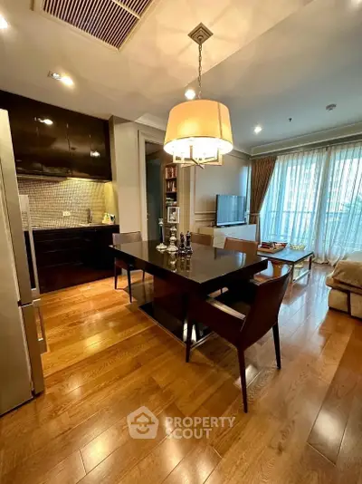 Elegant dining area with wooden flooring and modern lighting in a stylish apartment.