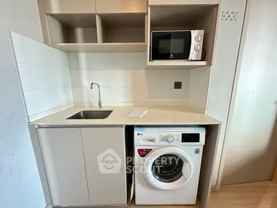 Compact kitchen with built-in washing machine and microwave, ideal for modern urban living.