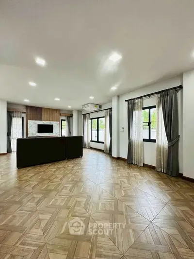 Spacious modern living room with elegant flooring and large windows for natural light.