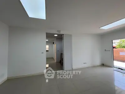 Spacious modern living room with sleek tile flooring and ample natural light.