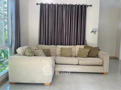 Spacious living room with cozy beige sofa and elegant curtains, perfect for relaxation and entertaining.