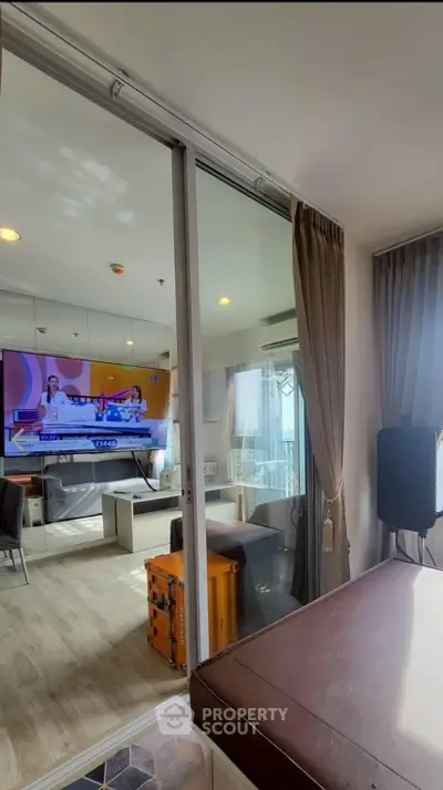 Modern living room with large glass doors and natural light, featuring a stylish TV setup and elegant decor.