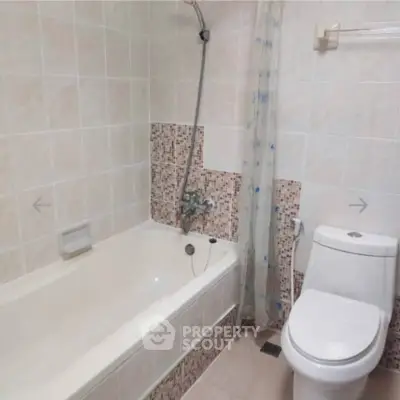 Spacious bathroom with bathtub and modern fixtures in a tiled setting.