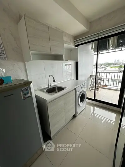 Modern kitchen with washing machine and balcony view in high-rise apartment