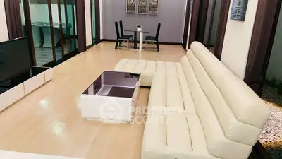 Spacious modern living room with elegant white leather sofa and sleek coffee table.