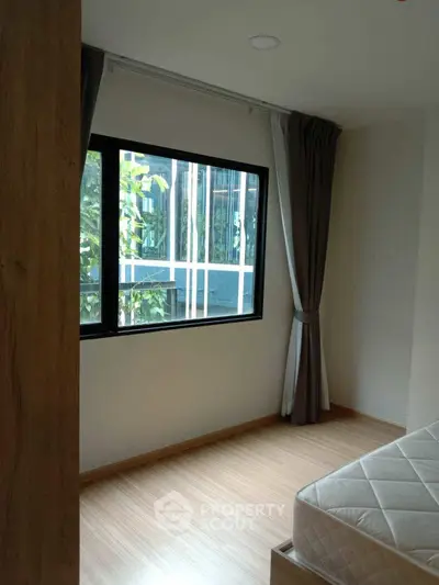 Bright bedroom with large window and wooden flooring, perfect for natural light lovers.