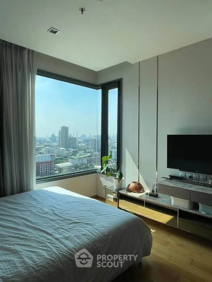 Modern bedroom with stunning city view, large window, and sleek furnishings in a high-rise apartment.