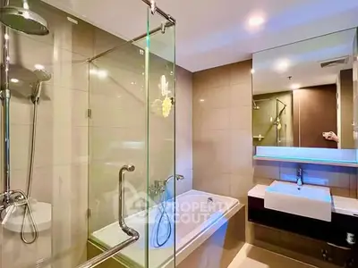 Modern bathroom with glass shower and bathtub in luxury apartment.
