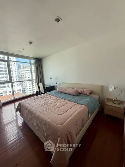 Spacious bedroom with large windows offering city views and modern furnishings.
