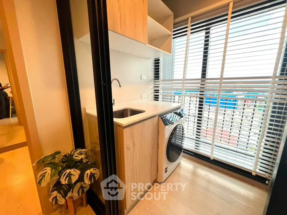 Modern laundry area with washing machine and large window in stylish apartment.