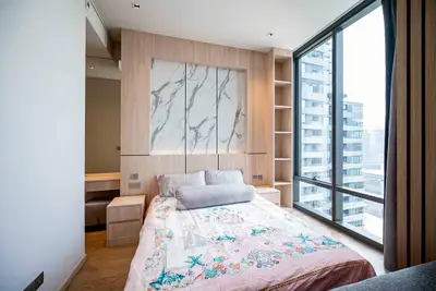 Modern bedroom with large window and city view in luxury apartment