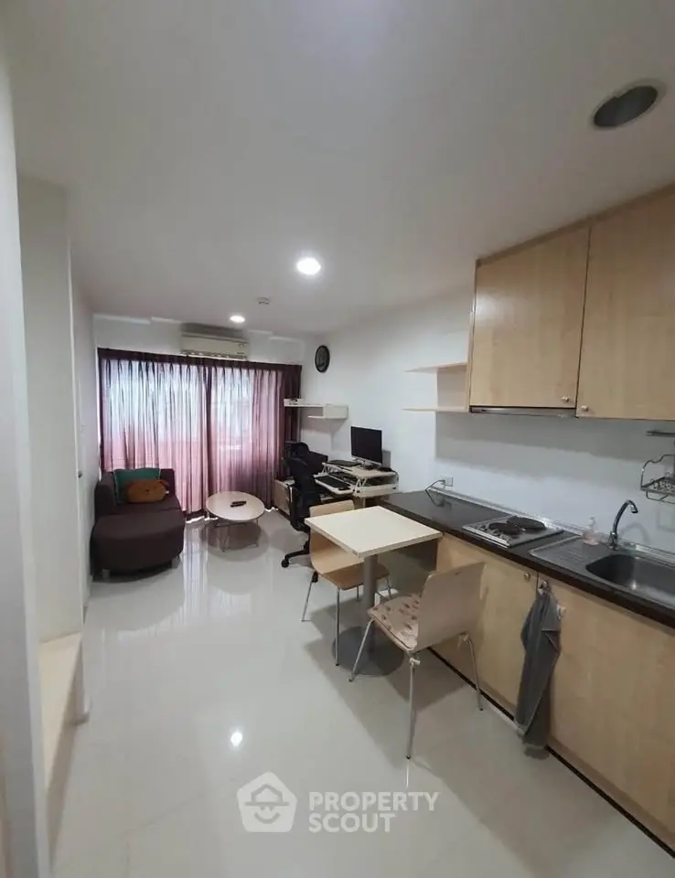 Modern studio apartment with open kitchen and cozy living area, featuring sleek cabinetry and natural light.