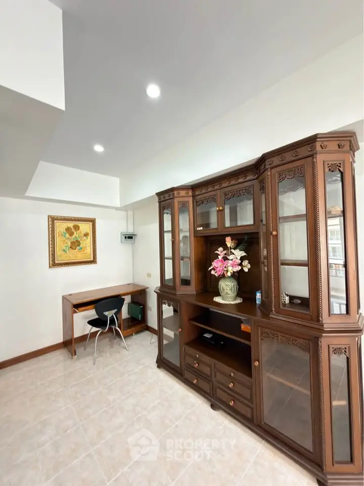Spacious living room with elegant wooden cabinet and cozy study corner, perfect for modern living.