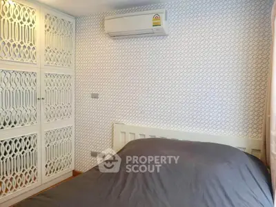 Cozy bedroom with stylish patterned wallpaper and built-in wardrobe