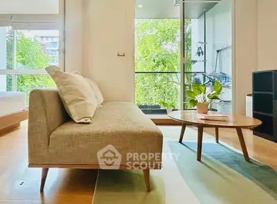 Modern living room with stylish sofa and coffee table, overlooking a lush green balcony view.