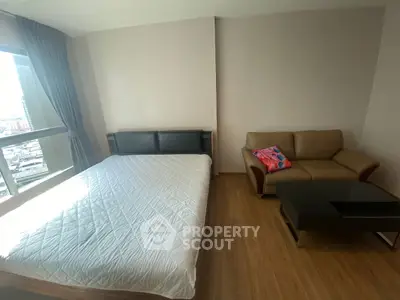 Modern bedroom with city view, featuring a cozy bed and stylish sofa.