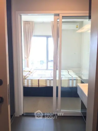 Modern bedroom with large window and sliding glass door, featuring a cozy bed and stylish decor.
