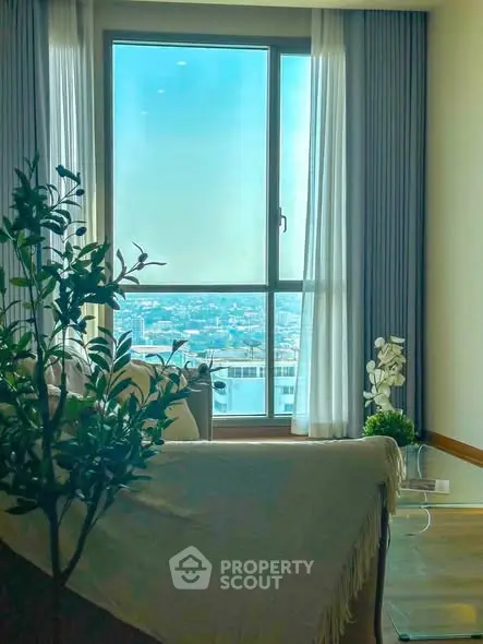 Bright living room with large window offering stunning city view and cozy decor.