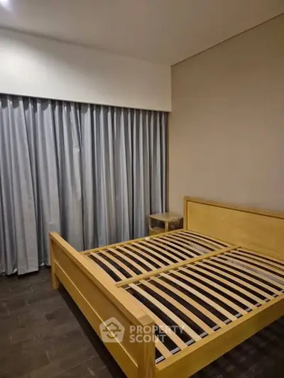 Spacious bedroom with wooden bed frame and elegant curtains