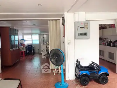 Spacious living area with tiled flooring and ample natural light, featuring a toy car and fan.