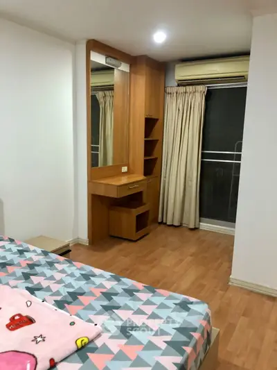 Cozy bedroom with wooden flooring and built-in vanity near window