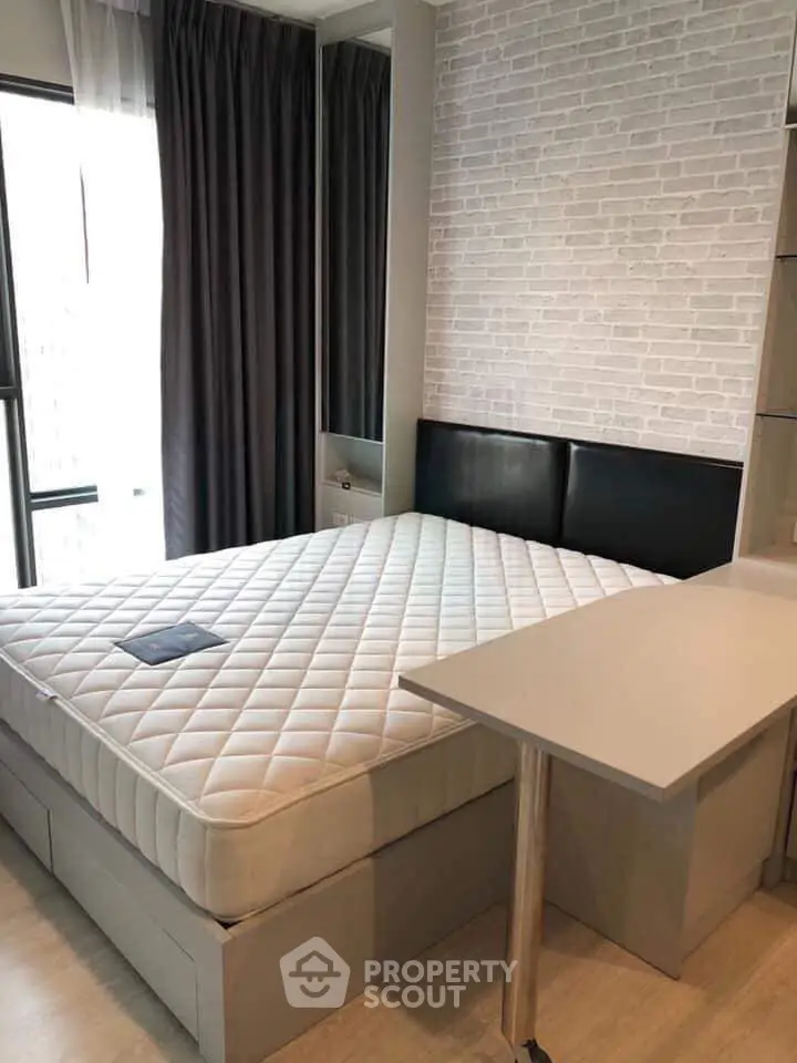 Modern bedroom with stylish brick accent wall and comfortable bed in a cozy apartment.